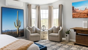 A bedroom with a large bed, two armchairs, a nightstand, a wooden dresser, and a window with curtains. - Cowboys & Roses - Wine Country Home w/Game Room, Hot Tub & Views - Dogs Welcome! (Cornville)