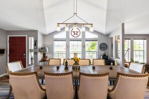 A dining room with a large wooden table, six chairs, and a chandelier.