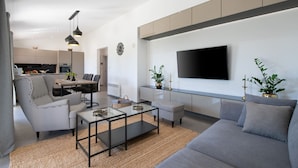 A modern living room with a sofa, a coffee table, and a dining area with chairs and a table. - Villa Silentio with Jacuzzi and Pool (Mali Vareški)