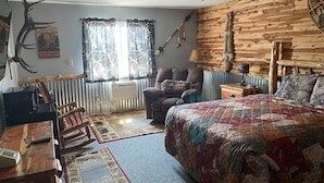 Ein gemütliches Zimmer mit einem Bett, einem Sessel, einem Schreibtisch und einer Heizung.