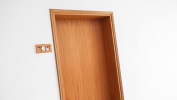 A wooden door with a simple design and a small, rectangular label on the wall to the left.