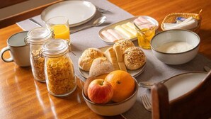 Une table de petit-déjeuner avec divers aliments et un verre de jus d’orange.