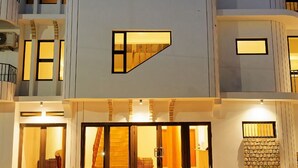 Un immeuble moderne à plusieurs étages, doté d’une entrée imposante avec des portes en verre et une façade en pierre.