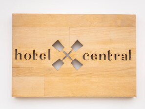 A wooden sign with the words "hotel central" and a cross design.