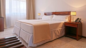 Une chambre d’hôtel avec un grand lit, deux tables de chevet, un bureau et une chaise.