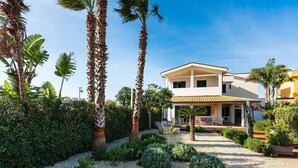 A two-story house with a covered patio, surrounded by palm trees and well-maintained gardens. - Corrado Residence-Verde Blu - Apartment near beach (Reitani)