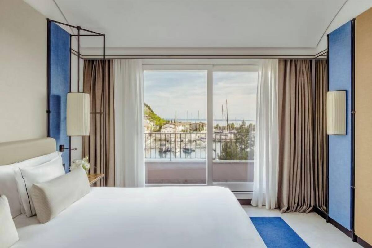 A hotel room with a large bed, a view of the sea, and a balcony.