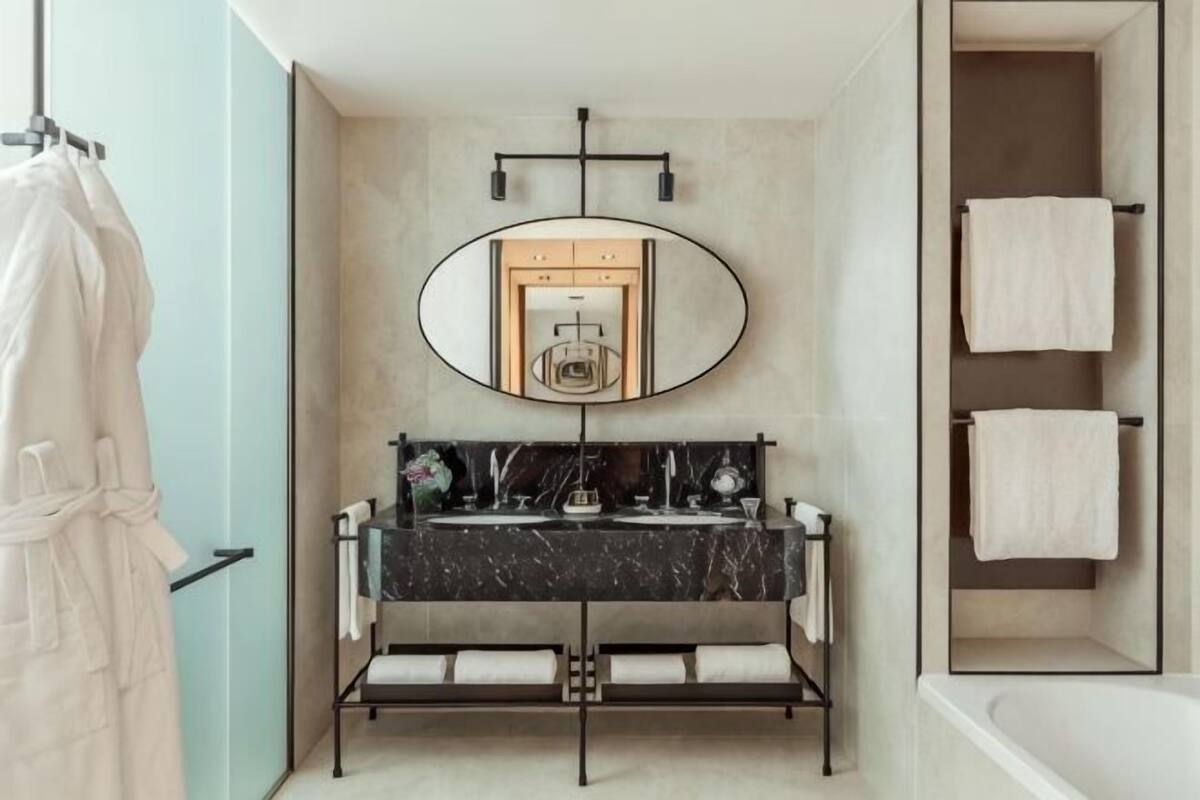 A bathroom with a marble sink, a large mirror, and a towel rack.
