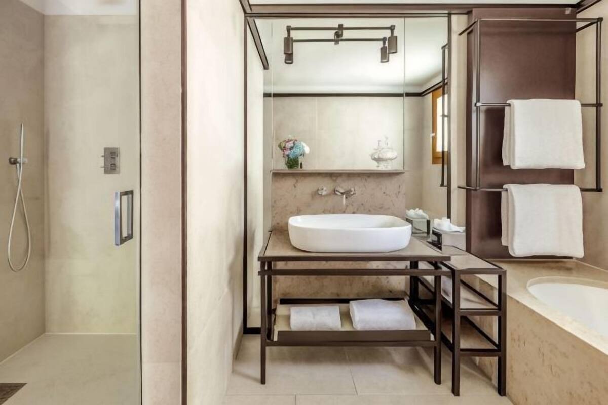A modern bathroom with a large sink, mirror, and shower.