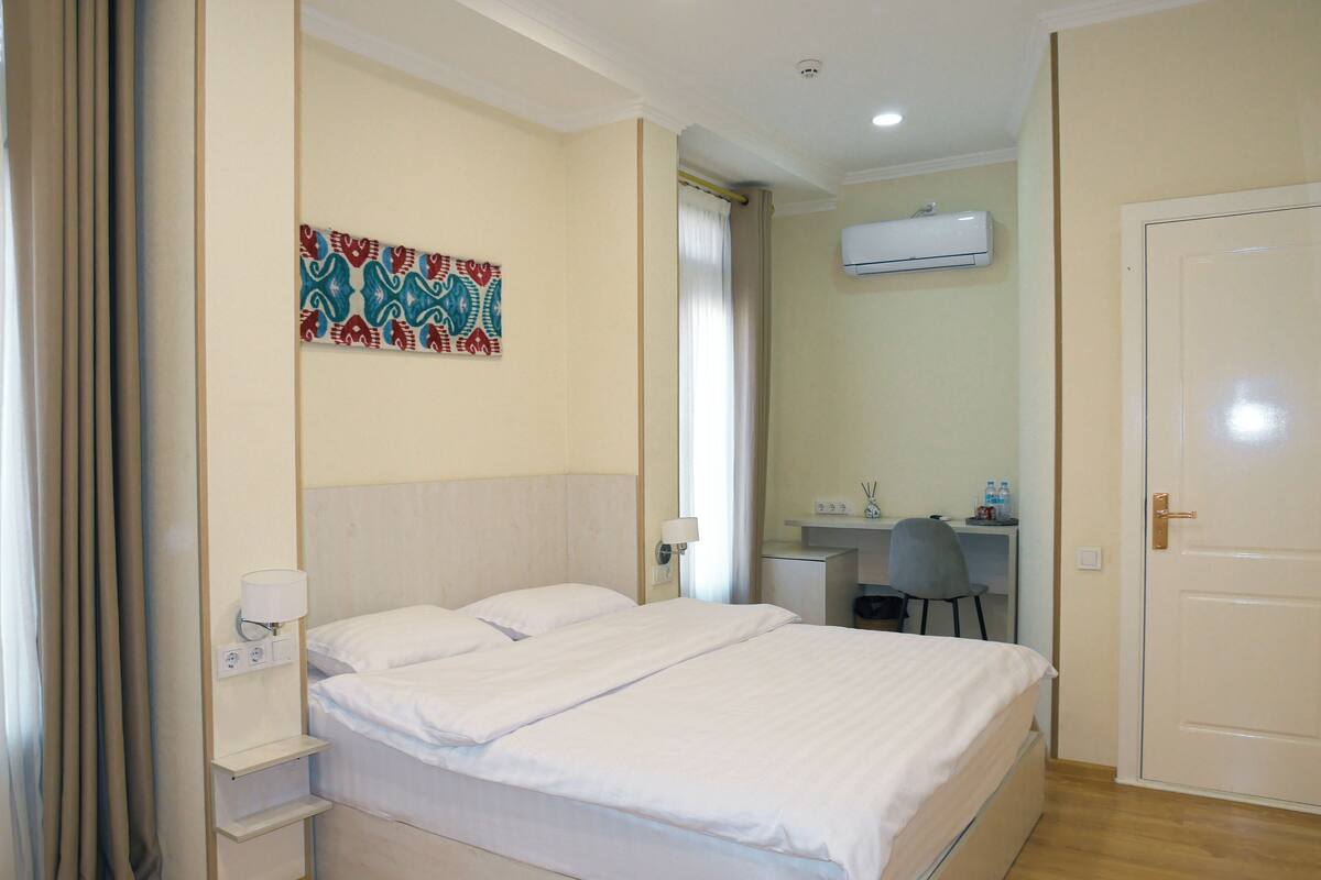 Een hotelkamer met een bed, een bureau en een airconditioning.