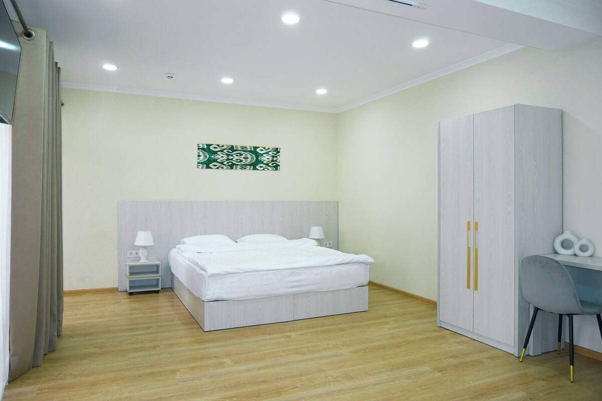 Een moderne slaapkamer met een bed, nachtkastjes, een bureau en een kledingkast.
