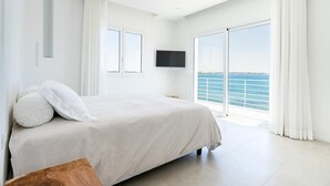 A spacious bedroom with a large bed, a flat-screen TV, and a balcony with a sea view. - Villa Finestrella, Seafront with pool (Arenella)