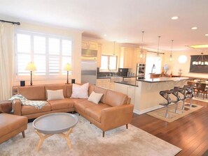 Relax in a comfortable living area with a sofa and coffee table, adjacent to a kitchen with stainless steel appliances and a bar.