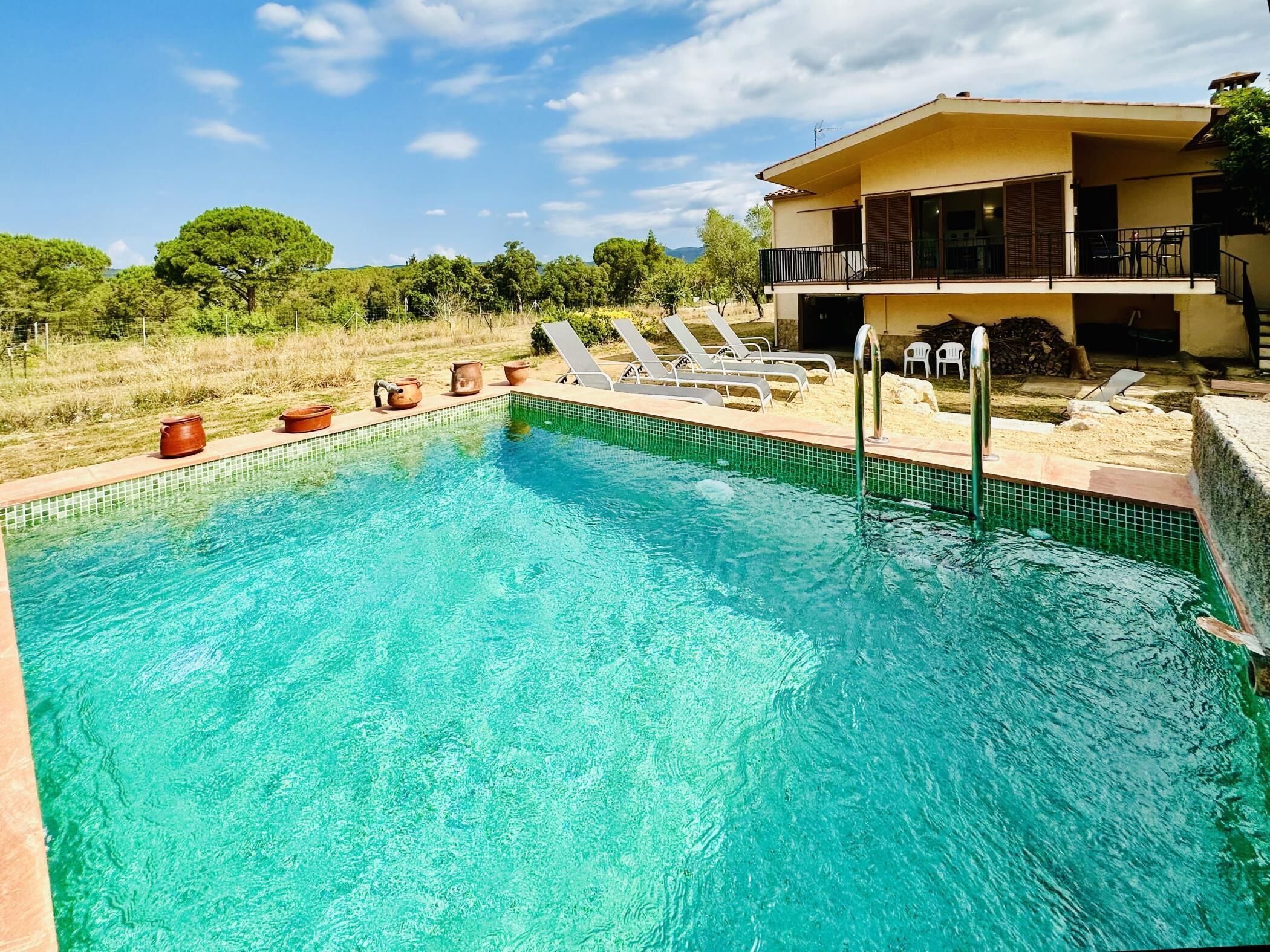 Ein Schwimmbecken mit Liegestühlen und ein Gebäude mit Balkon im Hintergrund.