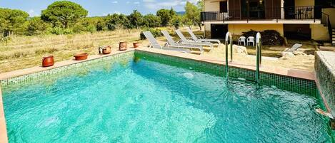 Ein Schwimmbecken mit Liegestühlen und ein Gebäude mit Balkon im Hintergrund.