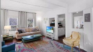 Uma sala de estar moderna com sofá, mesa de centro, televisão e um tapete estampado.