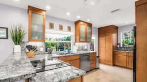 A modern kitchen with granite countertops, wooden cabinets, and a built-in dishwasher. - Enchanting Wilton Manors Haven: Outdoor Oasis (Wilton Manors)