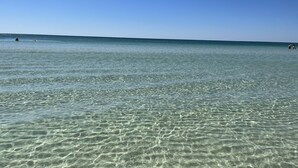 Vista despejada de una playa con aguas tranquilas y una costa lejana.
