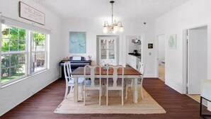 Un comedor con una mesa y sillas de madera, una araña y un piano.