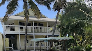 A swimming pool with a white fence, lounge chairs, and a two-story building with balconies. - Ocean Pearl On The Beach Villa , ManOWar Cay, Abaco, Bahamas (Man-O-War Cay)