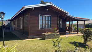 Una casa de madera con porche cubierto, una jardinera de piedra y un césped bien cuidado.