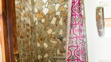 A shower with mosaic tile walls and a patterned shower curtain.