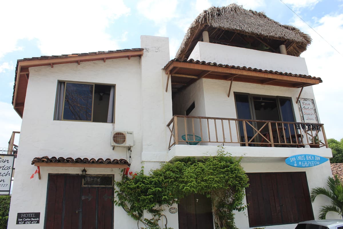A two-story building with a balcony, a thatched roof, and a sign indicating it is a hotel.