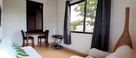 Une pièce comprenant un lit, un canapé, un bureau et une chaise. Il y a une fenêtre avec des rideaux.