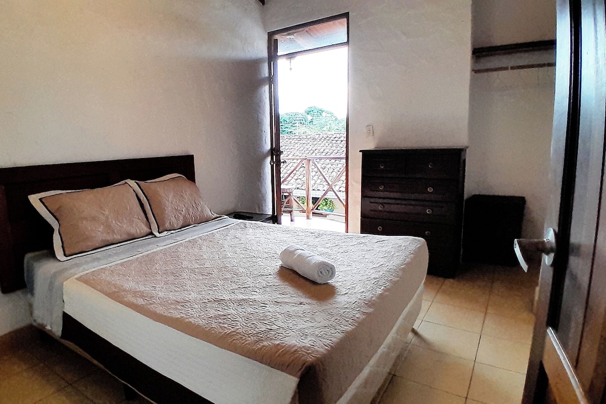 A bedroom with a bed, a dresser, and a door leading to an outdoor area.