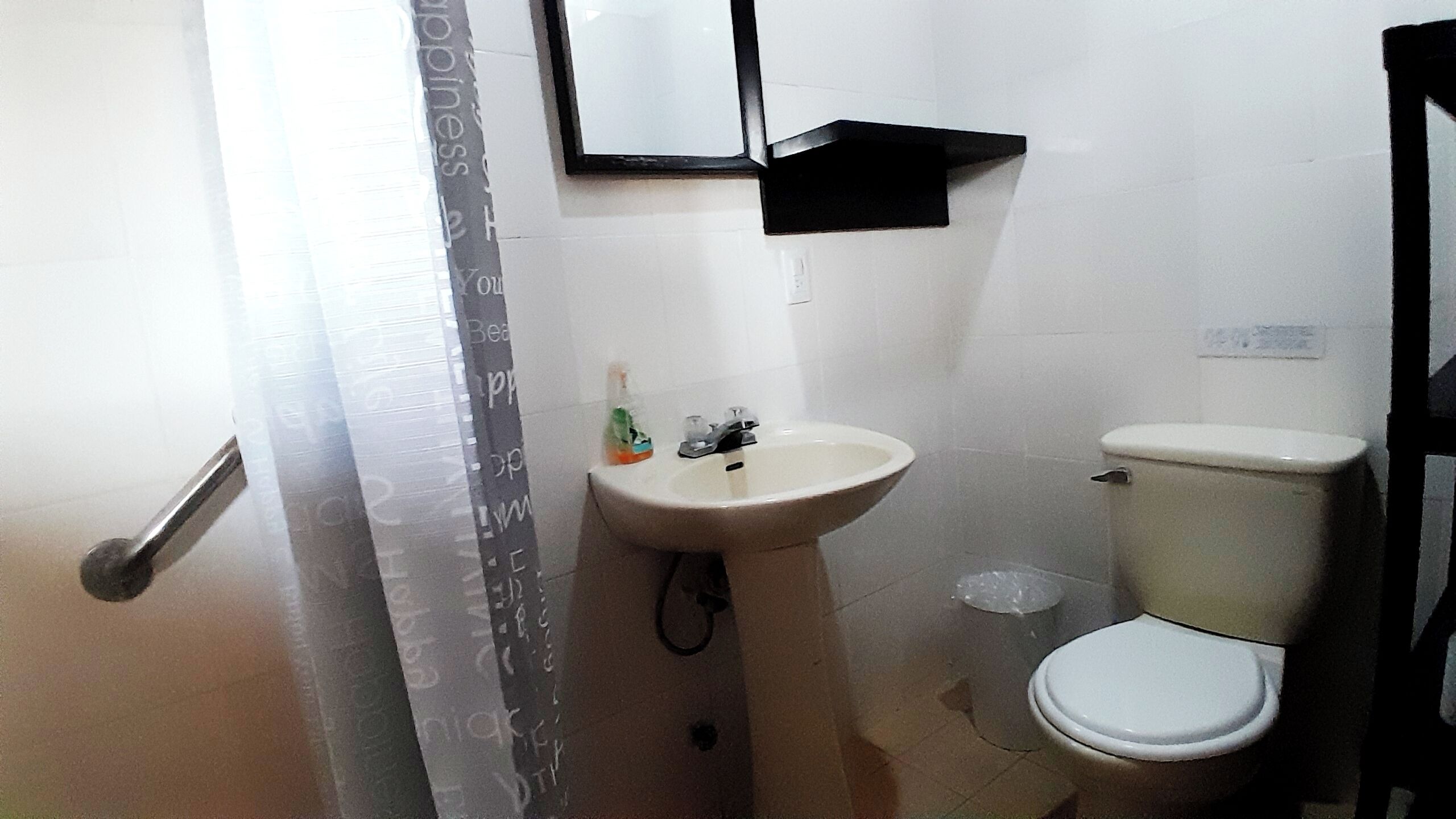 Een badkamer met een witte wastafel, een toilet en een spiegel boven de wastafel.