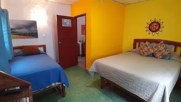 A room with two beds, a wooden headboard, a door, and a wall with a sun decoration.