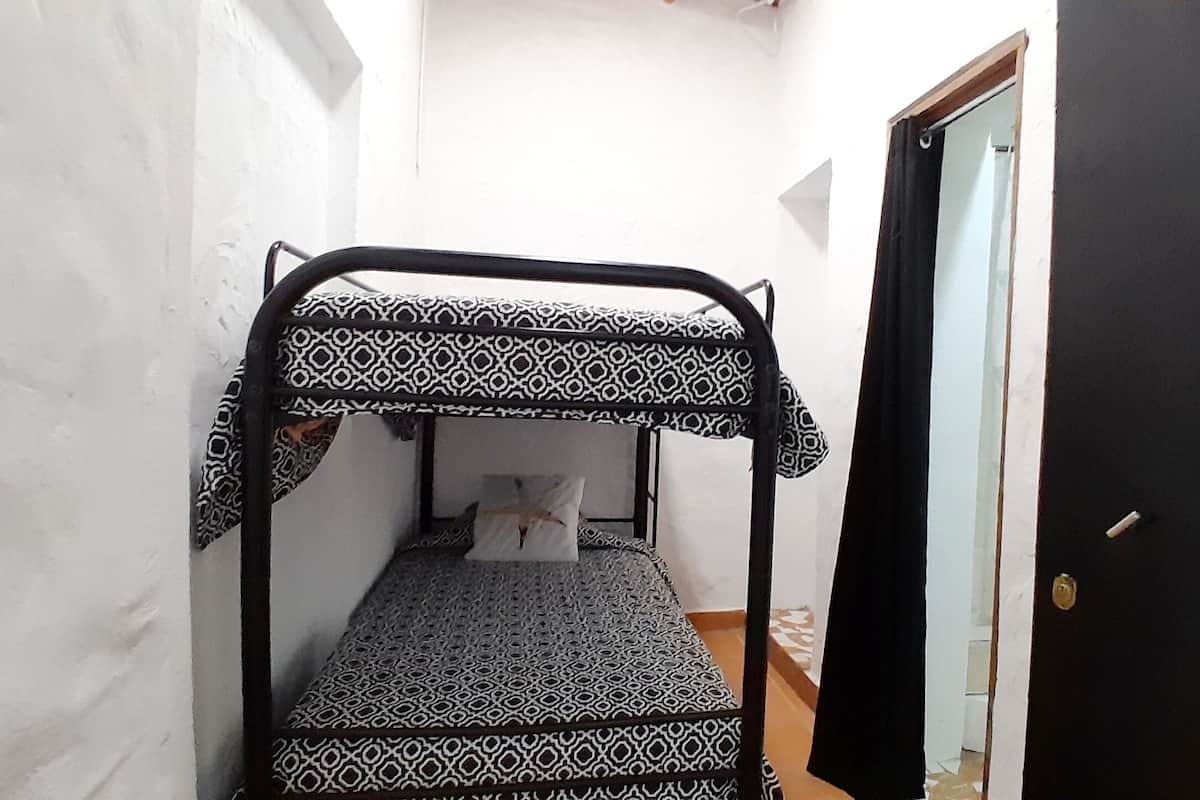 A narrow corridor with a bunk bed featuring a geometric patterned bedspread.