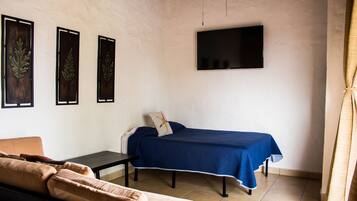 Ein Zimmer mit einem Bett, einem Sofa, einem kleinen Tisch und einem an der Wand befestigten Fernseher.