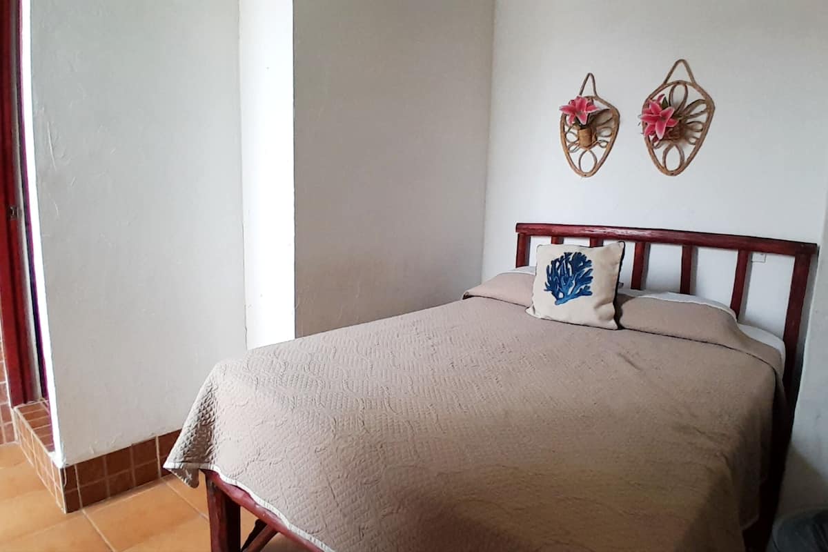 A bedroom with a bed, a pillow, and two wall decorations.