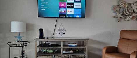 Ett vardagsrum med en platt-TV som är monterad på väggen och som visar gränssnittet för en streamingtjänst.