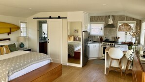 A compact bedroom with a bed, bedside table, and a small kitchenette.