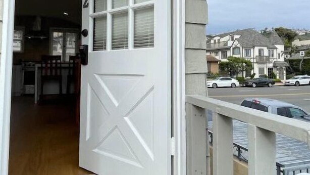 A white door with a number 2, leading to a kitchen with a wooden floor and a dining area.