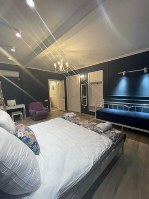 Ein Schlafzimmer mit einem großen Bett, einem Sessel, einem Schreibtisch und einem Kleiderschrank.