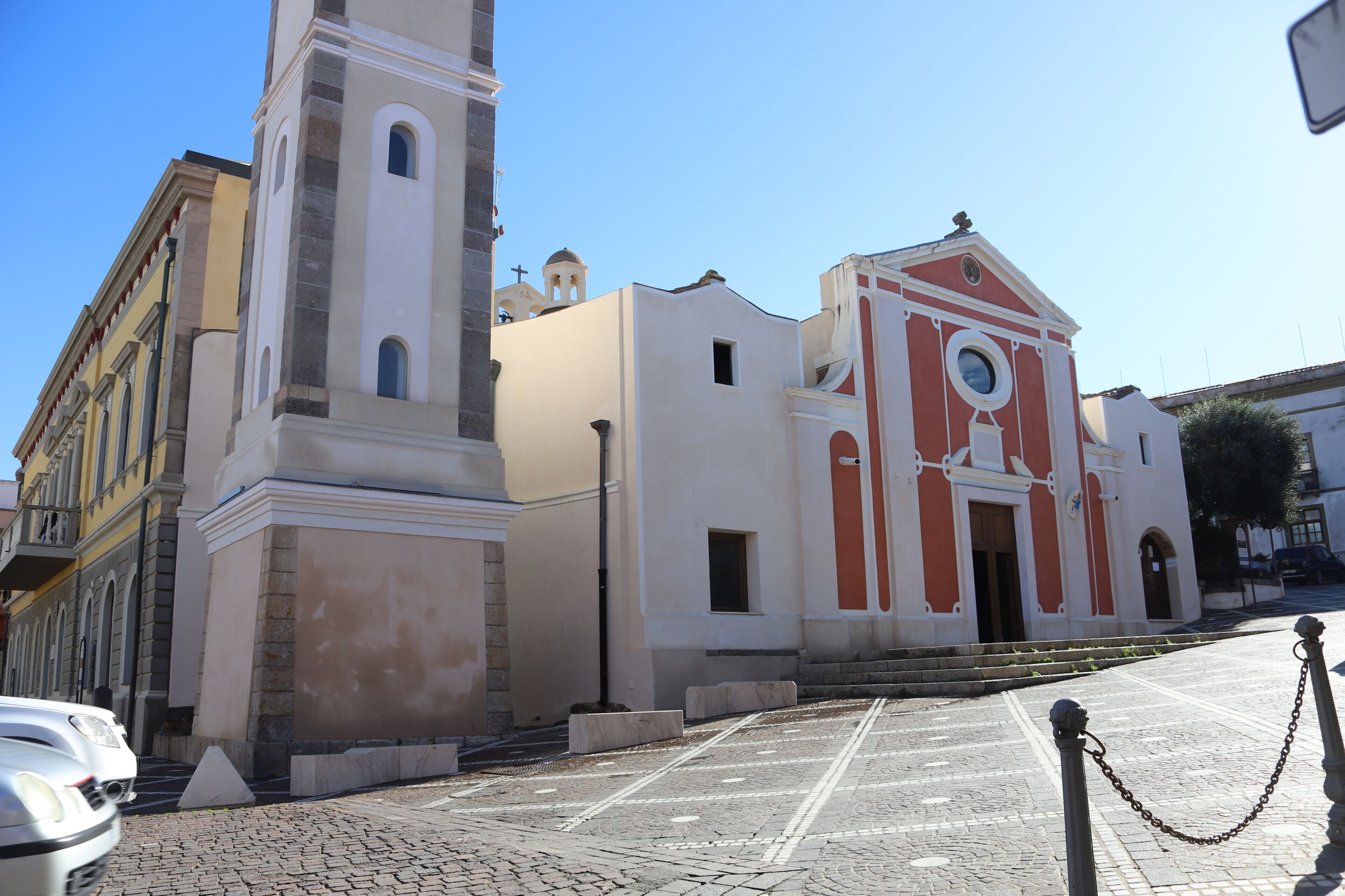 A church with a bell tower, a clock, and a cobblestone street.