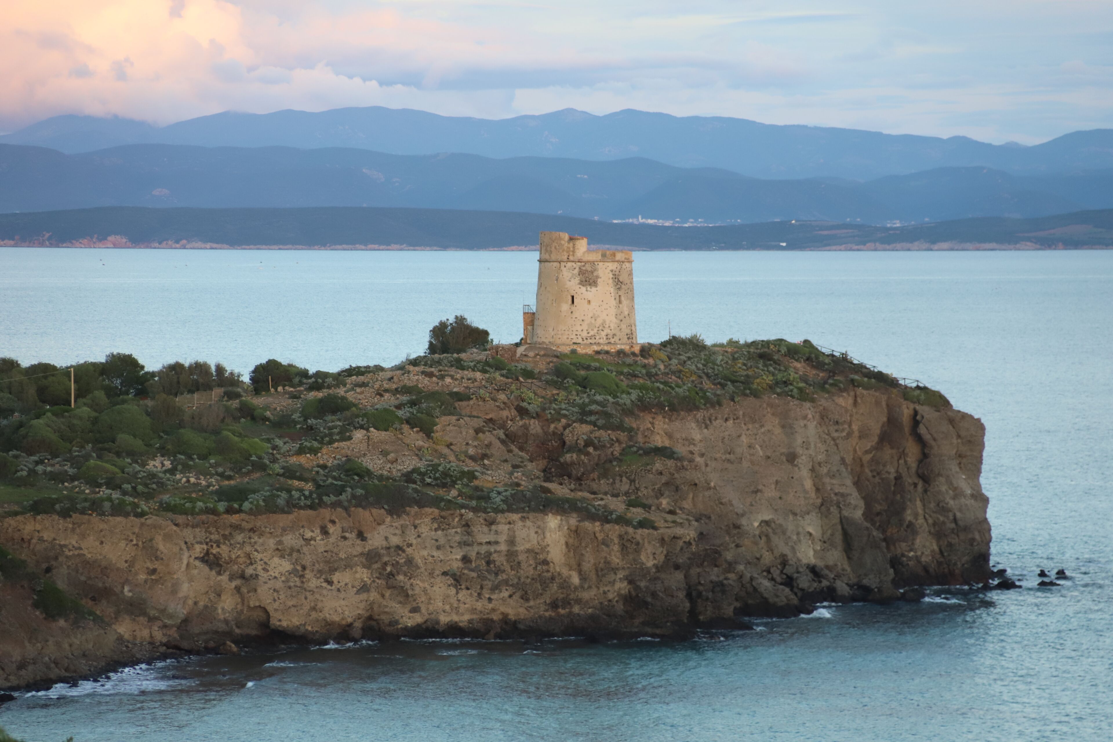 A coastal landscape with a prominent tower on a cliff overlooking the sea.