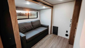 Un espace de vie compact comprenant un canapé, une fenêtre et une porte.