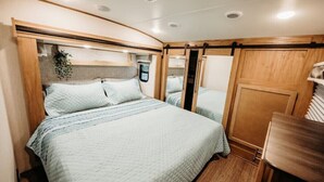 Une chambre compacte dans un camping-car, avec deux lits, un lambris en bois et une petite table.