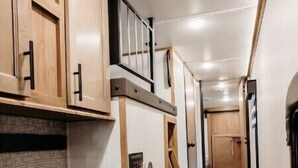 Un couloir étroit avec des armoires en bois et un escalier.