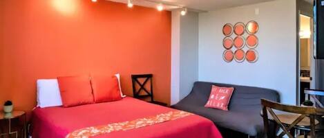 A room with a large bed, a sofa, a TV, and a small table.