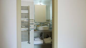 Een badkamer met een handdoekhouder, een wastafel, een spiegel en een betegelde spatwand.