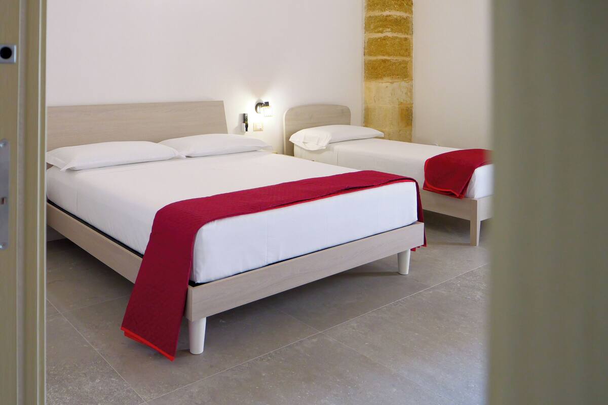 A hotel room with two beds, a stone accent wall, and a modern design.
