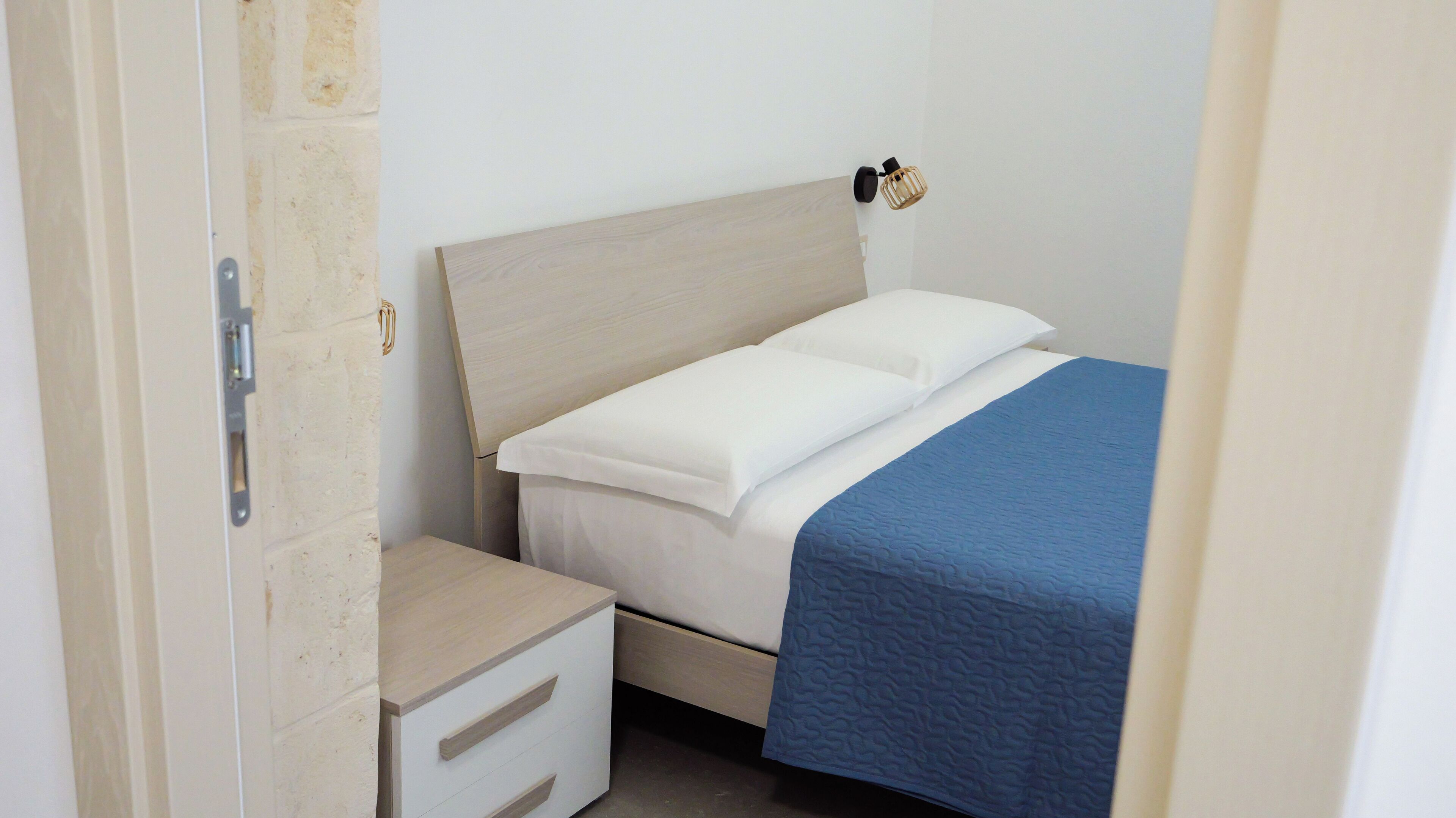 A bedroom with a bed, a nightstand, and a wooden drawer unit.