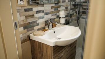 A bathroom with a white sink, a mirror, and a shower.