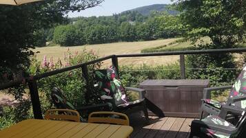 A wooden deck with outdoor furniture, including a table and chairs, and a large umbrella providing shade.