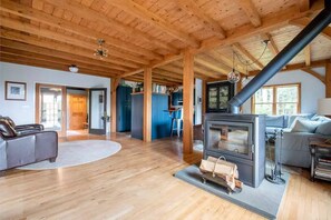 Cozy living area with a fireplace, sofa, and armchair, offering comfortable seating and a large window.